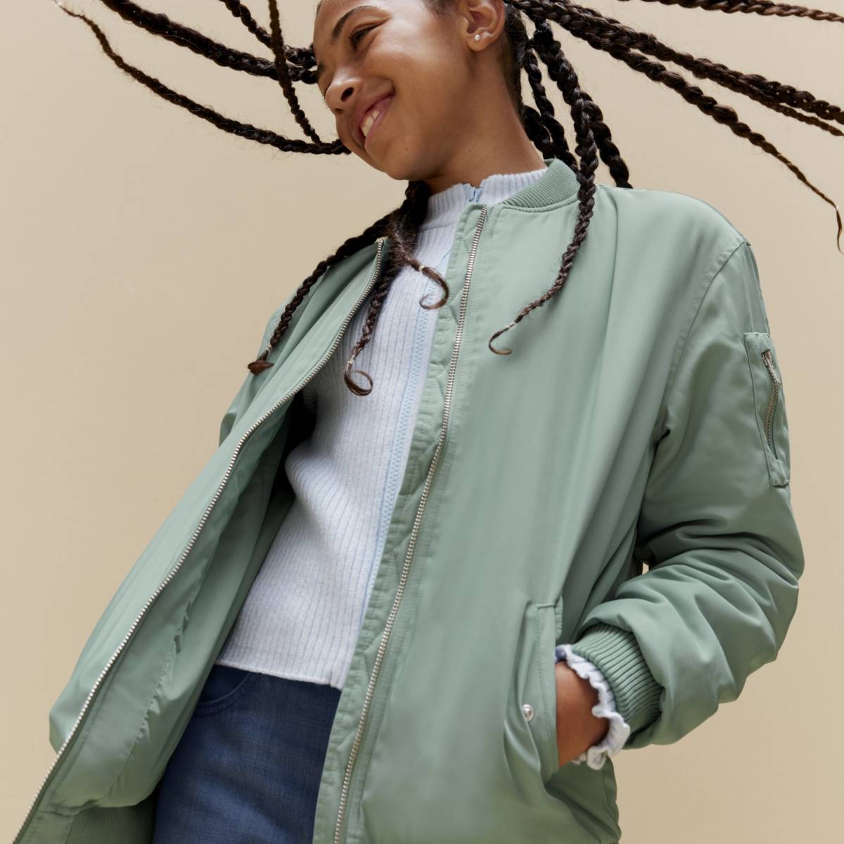 Girl wearing green bomber jacket, white top and jeans 